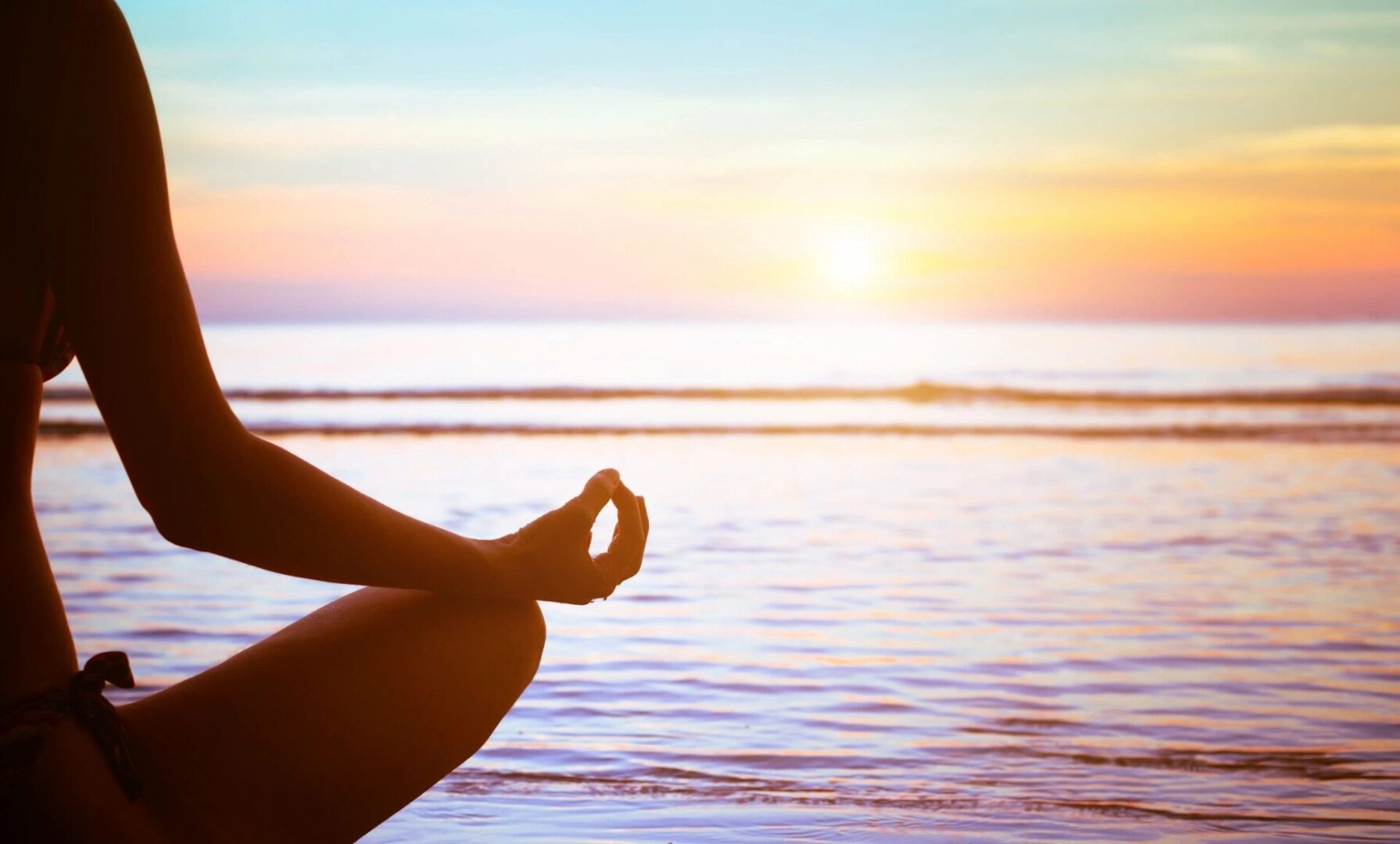 A person sitting in the lotus position on the beach